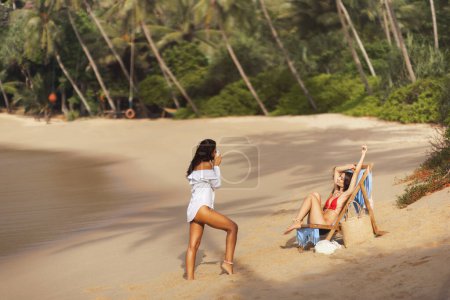 Téléchargez les photos : Une magnifique jeune femme posant en bikini sur une plage tropicale, prenant la photo parfaite pour sa séance photo romantique. - en image libre de droit