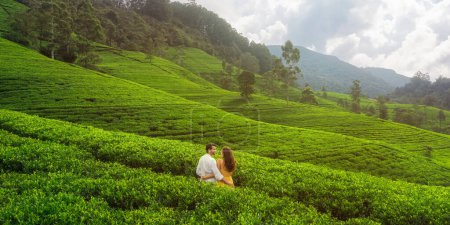 Photo for Natures background tea hills landscape with a romantic couple of travelers in love standing against embracing and looking away. Nuwara Eliya in Sri lanka - Royalty Free Image
