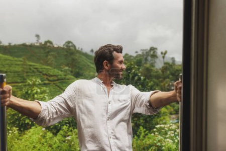 Foto de Viajes y exploración del hombre turístico en tren a lugares famosos de Sri Lanka. Viaje turístico por el país tropical. Viaje de Nuwara Eliya a Ella entre montañas y plantaciones de té. Extremo. - Imagen libre de derechos