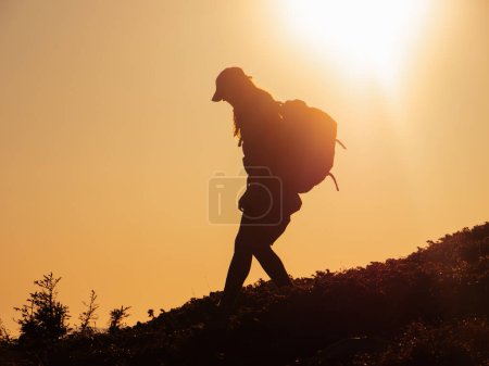 Photo for Silhouette of hiker tourist woman with backpack during mountain trekking from the top. - Royalty Free Image