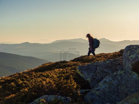 Téléchargez les photos : Descente de la randonneuse touristique femme avec sac à dos pendant la randonnée en montagne depuis le sommet. - en image libre de droit