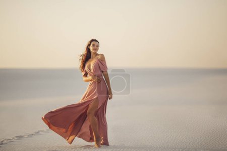 Téléchargez les photos : Voyage et joie de la beauté du désert. Modèle femme romantique à la mode dans le désert en robe rose du soir. Superbe fille mince à l'extérieur. Photo de haute qualité - en image libre de droit