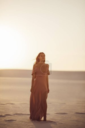 Téléchargez les photos : Modèle femme romantique à la mode dans le désert en robe rose du soir. Superbe fille mince à l'extérieur. Photo de haute qualité - en image libre de droit