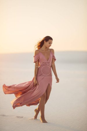 Foto de Caminando romántico modelo de moda mujer en el desierto en vestido de noche rosa. Hermosa chica delgada al aire libre. Foto de alta calidad - Imagen libre de derechos