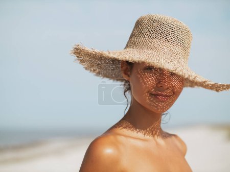Beach sun hat woman on vacation. Close-up of a girls face in straw sunhat enjoying the sun looking at the camera. Stickers 706878348