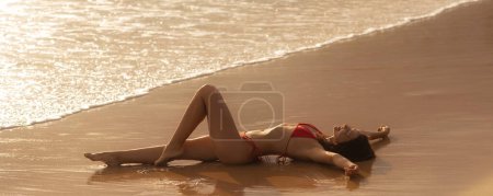 Foto de Seductora mujer de vacaciones en bikini de playa tendida en la playa en sensación de libertad, disfrutando de su ocio de verano. Feminidad y belleza femenina foto de alta calidad - Imagen libre de derechos