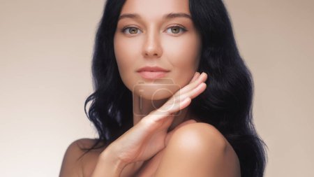 Photo for Happy beautiful young adult woman touching her perfect face with healthy shiny skin, hand on chin. Beauty banner photo of gorgeous girl after morning beauty cosmetic routine finishes daily makeup on - Royalty Free Image