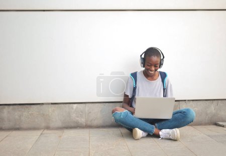 Foto de Mujer joven sentada con su espalda a una pared funciona con una computadora - Imagen libre de derechos