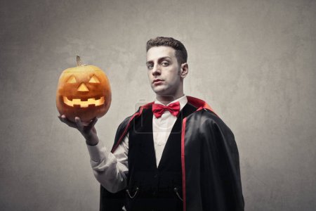 Photo for Portrait of man disguised as Dracula with a halloween pumpkin in his hand - Royalty Free Image