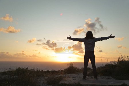 Téléchargez les photos : Homme par derrière les bras ouverts devant un coucher de soleil - en image libre de droit