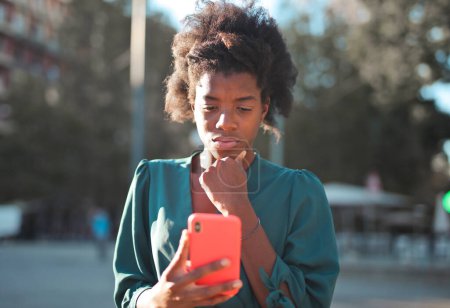 Foto de Mujer joven preocupada con un teléfono inteligente en las manos - Imagen libre de derechos