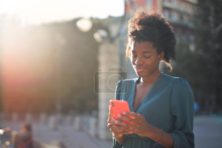 Photo for Young woman uses a smartphone in the city - Royalty Free Image