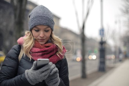 Téléchargez les photos : Portrait de jeune femme dans la rue avec un smartphone - en image libre de droit