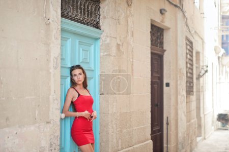 Téléchargez les photos : Jeune femme appuyée contre la porte d'une maison - en image libre de droit