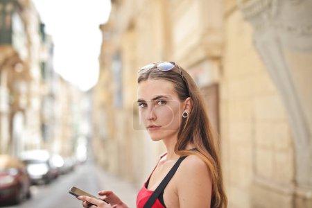 Photo for Portrait of young woman while using a smartphone - Royalty Free Image