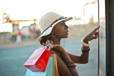 Téléchargez les photos : Jeune femme à l'arrêt de bus avec quelques sacs à provisions - en image libre de droit