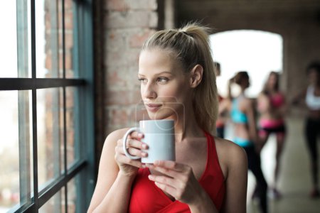Photo for Portrait of young woman in a gym while drinking from a cup - Royalty Free Image