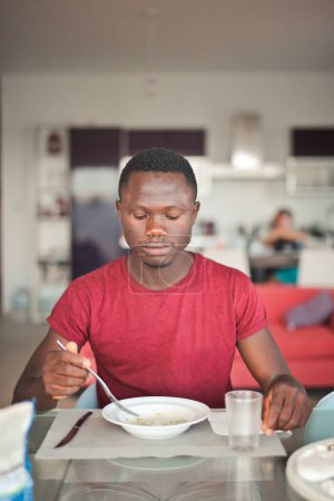 Photo for Young man eats rice in the kitchen - Royalty Free Image