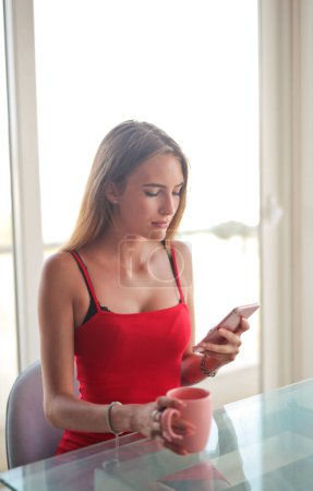 Photo for Young woman uses a smartphone at home - Royalty Free Image