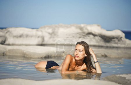 Téléchargez les photos : Jeune femme se repose sur une plage - en image libre de droit