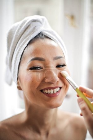 Foto de Joven asiático mujer sonriendo durante maquillaje sesión - Imagen libre de derechos