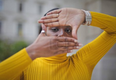 Foto de Mujer negra adulta forma un marco alrededor de sus ojos con sus manos - Imagen libre de derechos