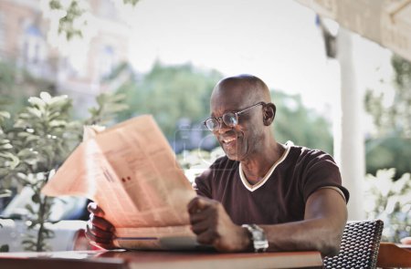 Foto de Hombre adulto lee un periódico en un café - Imagen libre de derechos