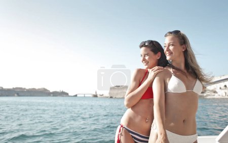 Foto de Dos mujeres jóvenes en un yate mirar a la isla que están alcanzando - Imagen libre de derechos