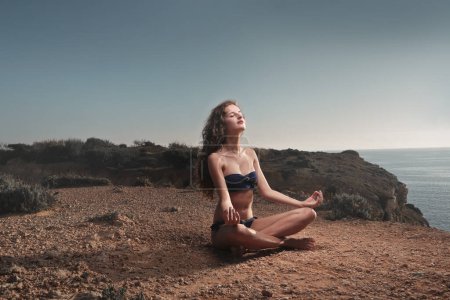Photo for Young woman practices yoga on a beach - Royalty Free Image
