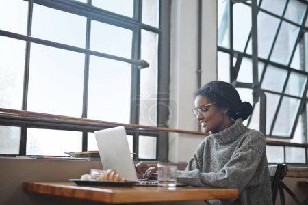 Foto de Mujer joven en un café utiliza una computadora - Imagen libre de derechos