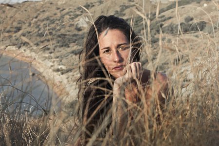 Téléchargez les photos : Jeune femme dépeinte derrière des plantes sur une plage à Malta - en image libre de droit