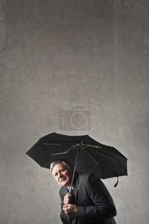 Photo for Scared elderly man with an umbrella - Royalty Free Image