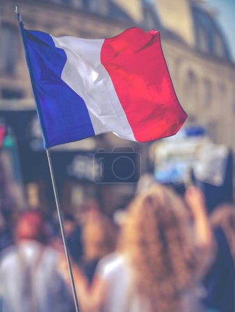 Una protesta en una calle de París con una bandera francesa en primer plano