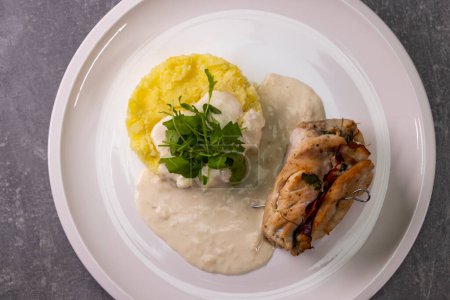 Téléchargez les photos : Rouleau de dinde rempli d'épinards et de jambon servi avec purée de pommes de terre et sauce à la crème - en image libre de droit