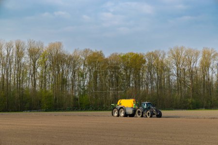 Foto de Tractor con pulverizador durante el trabajo de primavera en el campo - Imagen libre de derechos