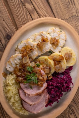 Photo for Smoked meat served with red and white cabbage and two kinds of dumplings - Royalty Free Image