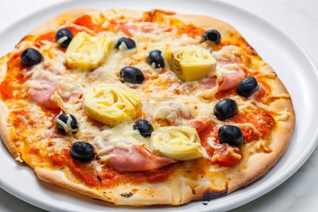 Foto de Pizza con jamón, aceitunas negras y alcachofas - Imagen libre de derechos