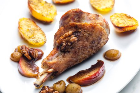 Photo for Poultry leg baked with fruit and walnuts served with fried potatoes - Royalty Free Image