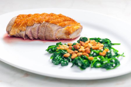Photo for Roasted duck breast served with salad of spinach leaves and pine nuts - Royalty Free Image