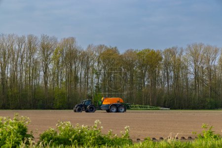 Téléchargez les photos : Tractor with sprayer during spring work on the field - en image libre de droit