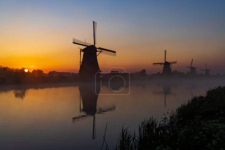 Photo for Traditional Dutch windmills with a colourful sky just before sunrise in Kinderdijk, The Netherlands - Royalty Free Image