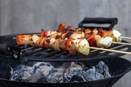 Téléchargez les photos : Brochette avec oignon poivron rouge et porc fumé sur un gril de jardin - en image libre de droit