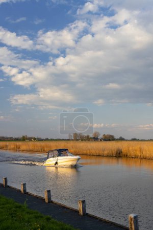 Photo for A water canal with a small boat nearby Steenwijk - Vollenhove  near Zwolle, The Netherlands - Royalty Free Image