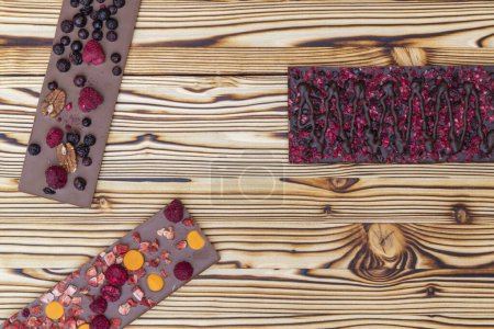 Photo for Different kinds of chocolate with dried fruits on a wooden board - Royalty Free Image