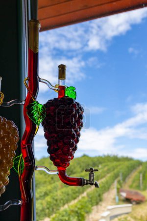 Photo for Glass carafe with white and red wine in the shape of a grape and vineyard background - Royalty Free Image