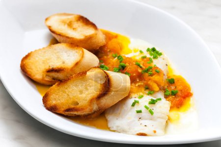 Photo for White fish with tomato sauce and roasted baguette slices - Royalty Free Image