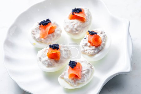 Foto de Huevos cocidos rellenos de atún, salmón ahumado y caviar negro en la parte superior - Imagen libre de derechos