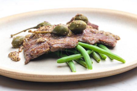 Photo for Pork steak with mustard sauce with capers served with green beans - Royalty Free Image