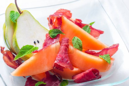 Photo for Melon cantaloupe and pear with  proscutto and mint leaves - Royalty Free Image