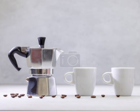 Photo for Metal geyser coffee maker on table with cups - Royalty Free Image